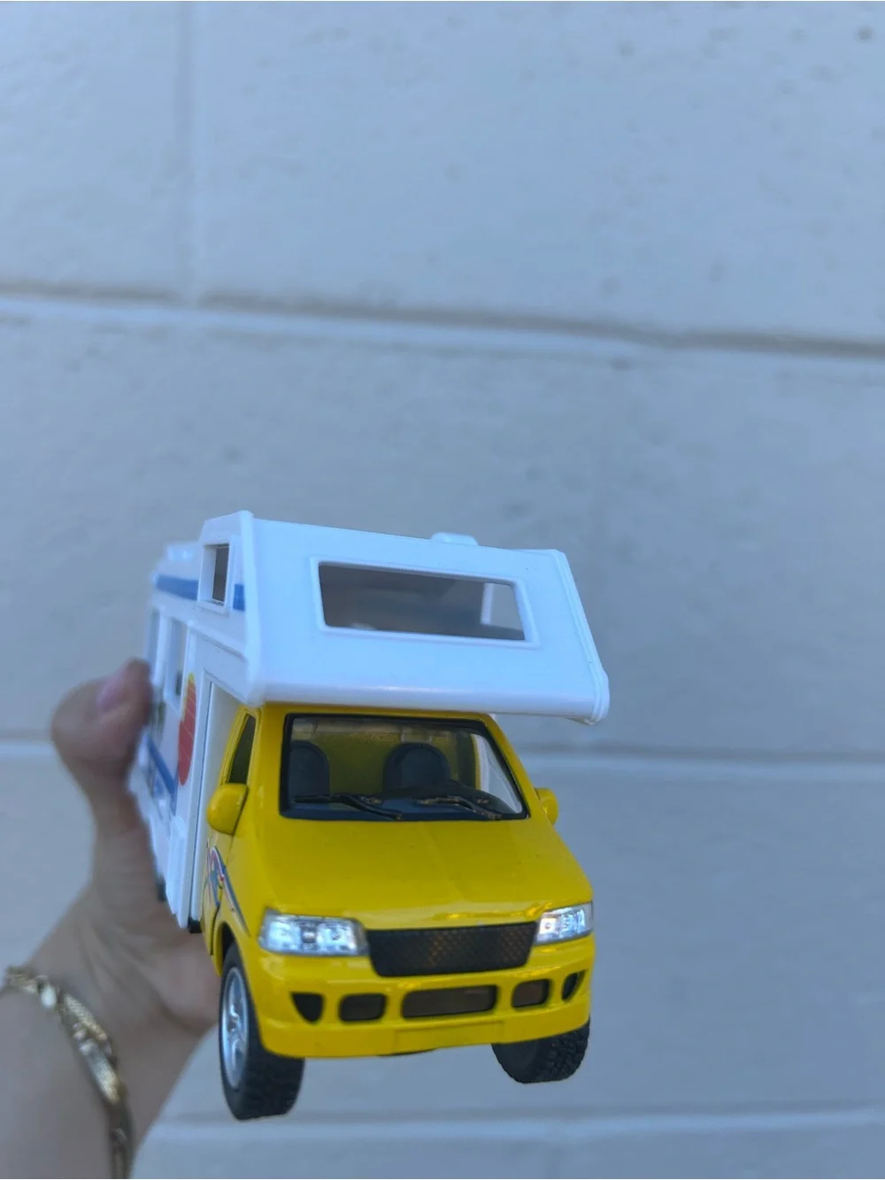 Bright yellow and white toy camper van with colorful beach graphics collectible